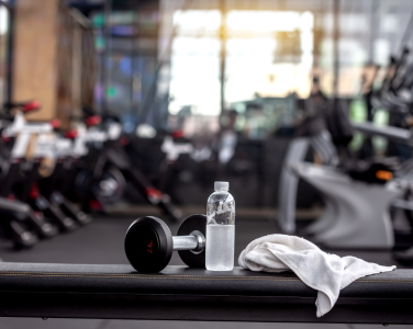 Poids, bouteille d'eau et serviette sur un banc. 