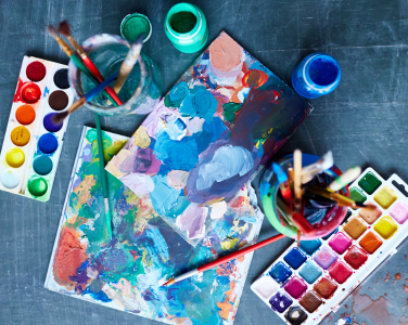 Du papier coloré, des pinceaux dans des bocaux et des palettes de peinture.