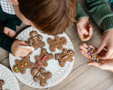 Des enfants décorent des biscuits au pain d'épices avec du glaçage et des bonbons.
