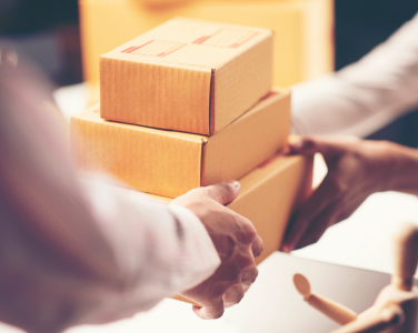 Deux personnes échangeant des cartons empilés.