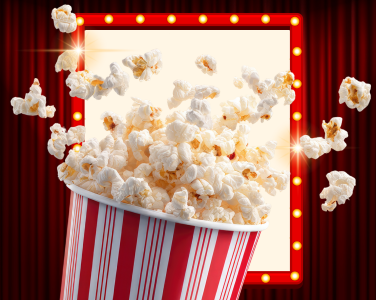 Du pop-corn jaillit d'un récipient rayé devant une enseigne lumineuse.