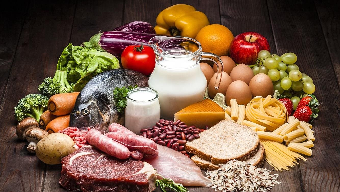 L’image présente un assortiment éclatant de poisson, lait, fromage, légumes, pain, œufs et fruits frais, magnifiquement disposé pour mettre en valeur la variété et la fraîcheur.