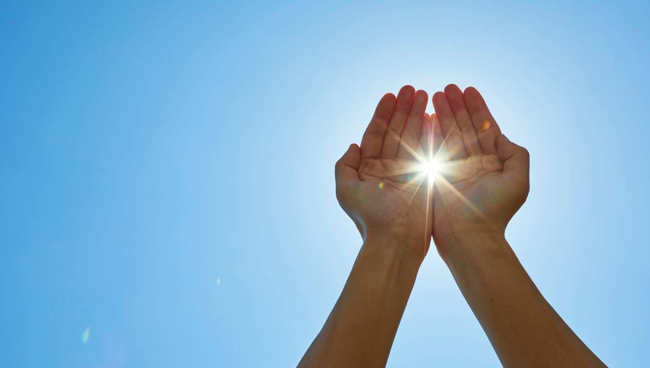 Des mains capturant la lumière contre un ciel clair