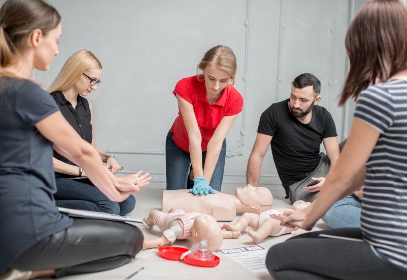 Jeune femme instructeur montrant comment effectuer des compressions thoraciques