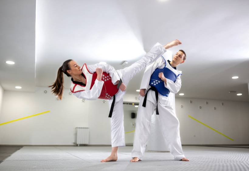 Jeune femme pratiquant l'art martial du taekwondo avec son entraîneur.