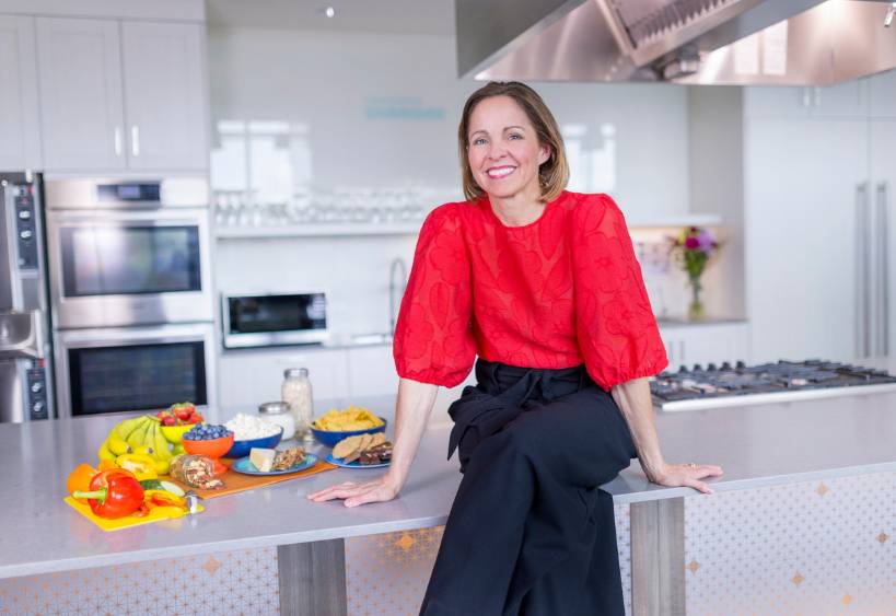 Andrea Holwegner assise sur le comptoir de la cuisine avec un assortiment d'aliments