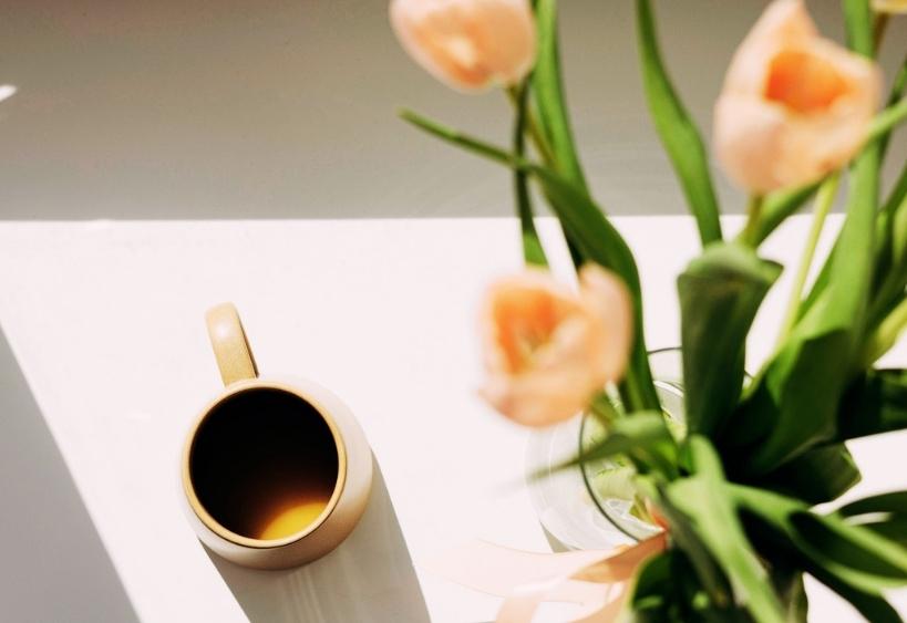 Tasse de café à côté d’un bouquet de tulipes roses