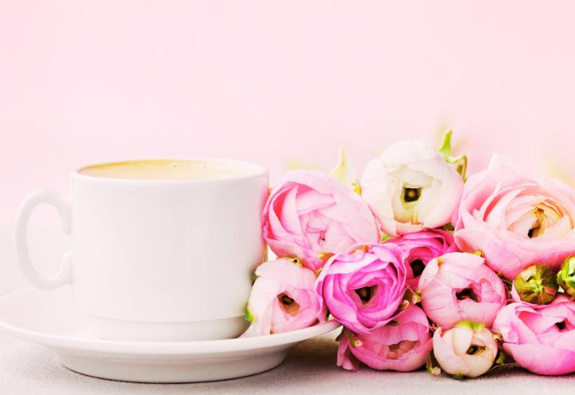 Tasse de café à côté d’un bouquet de roses