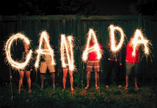 Groupe d'amis tenant des cierges magiques formant le mot « Canada ».
