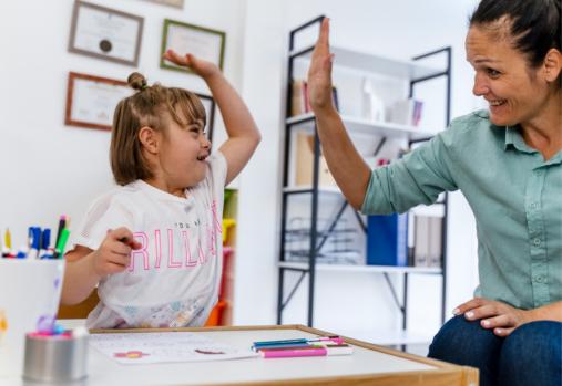  enseignante et petite fille ayant le syndrome de Down qui se tapent dans la main