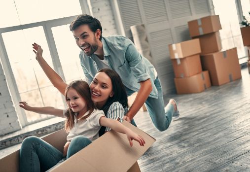 homme poussant une boîte avec une femme et une fille assises à l'intérieur