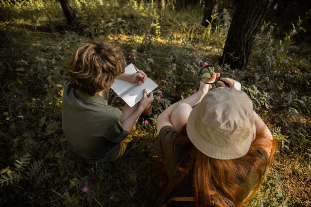 Deux enfants explorent une forêt, observant la nature à l'aide d'un carnet de croquis et d'une loupe