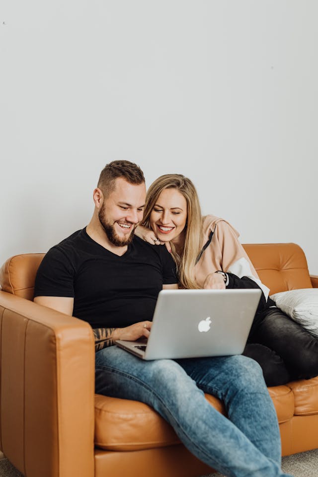 Un couple heureux profitant d'un moment de détente sur le canapé, devant leur ordinateur portable, à l'intérieur.