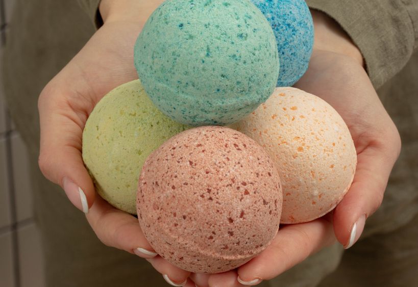 Des bombes de bain colorées sont présentées dans les mains d’une personne.