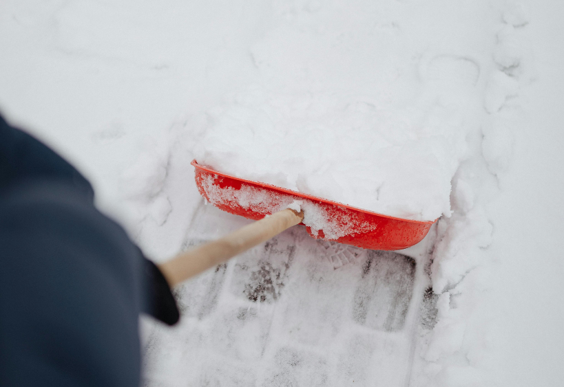 Trottoir enneigé en cours de déneigement avec une pelle 