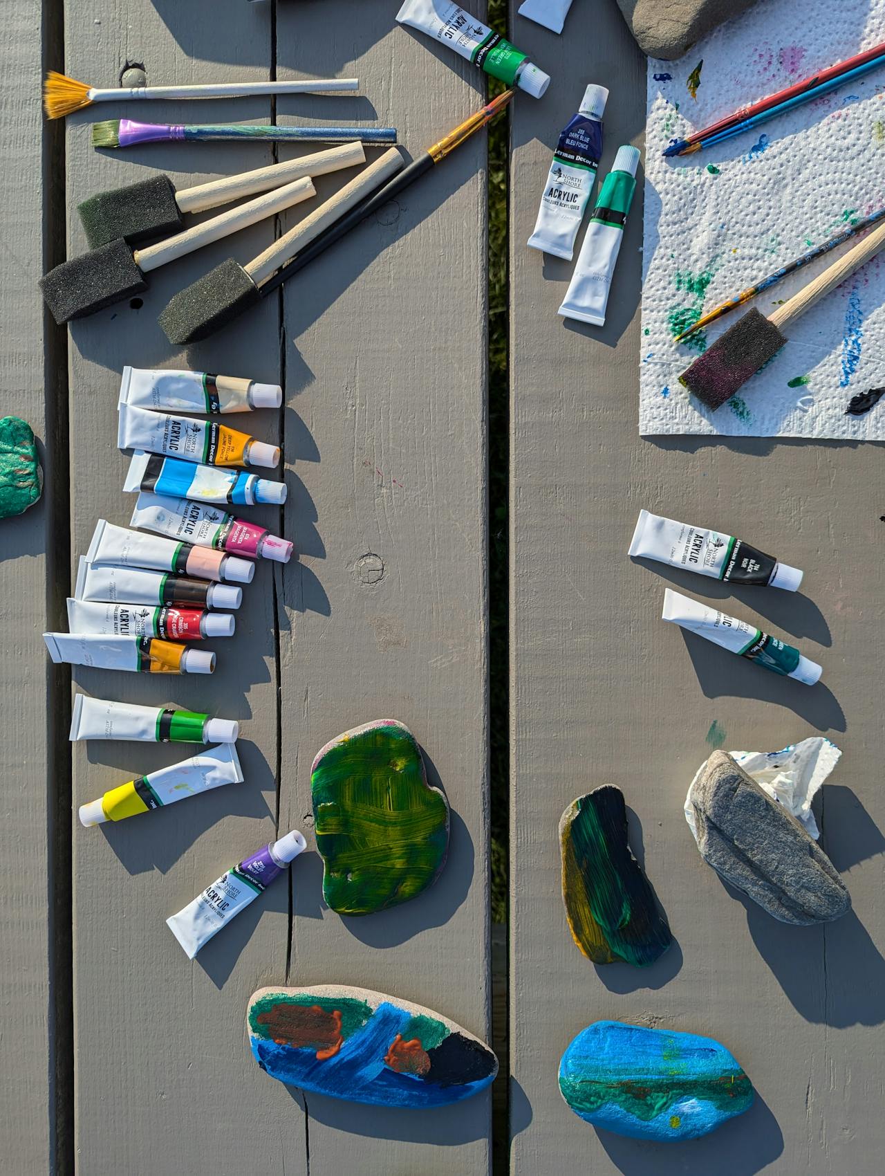 Peintures acryliques et pinceaux sur une table en bois à l’extérieur