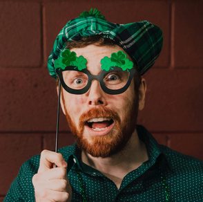 homme portant des vêtements de la Saint‑Patrick et des lunettes fantaisie, regardant la caméra avec une expression surprise