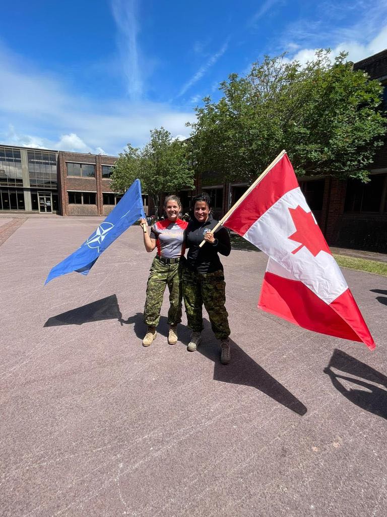 Claudine et Sarah-Emilie tenant un drapeau de l'OTAN et un drapeau canadien