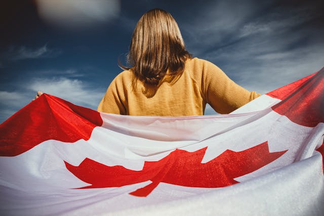 dos d'une femme enveloppée dans un drapeau canadien