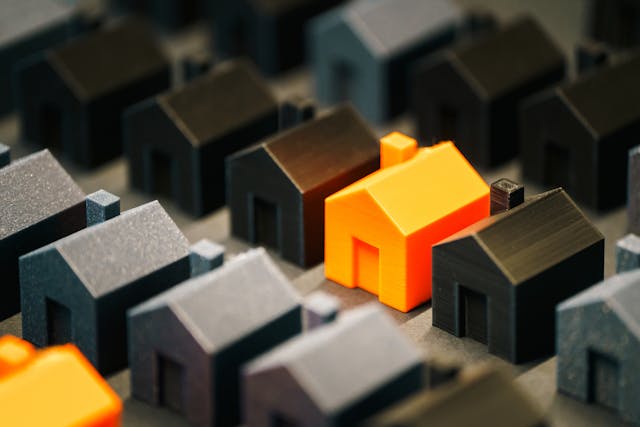 Une maison témoin orange au milieu de miniatures noires