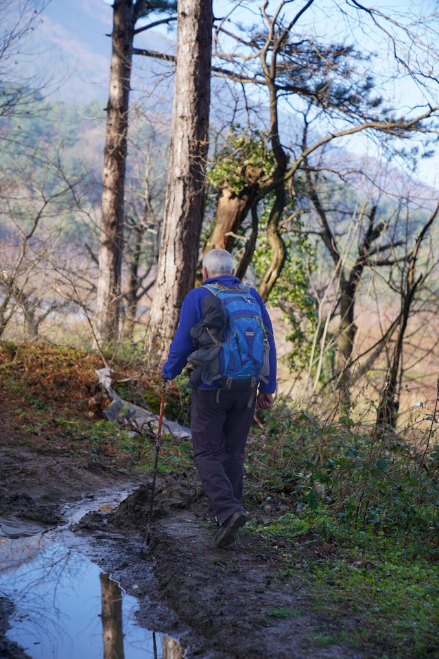 Un homme en randonnée sur un sentier forestier boueux