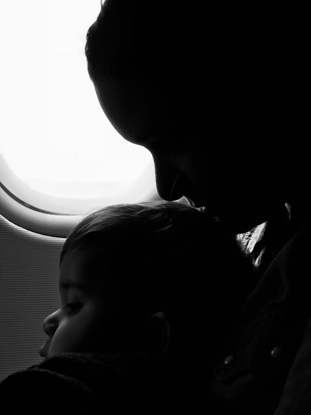 Photo en niveaux de gris d'une femme avec un bébé sur les genoux dans un avion