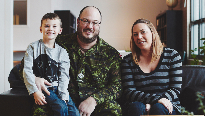 Un couple de militaires, souriant, prenant un café tout en regardant une tablette