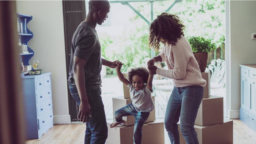 parents and child with cardboard moving boxes