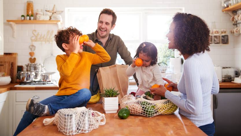 Une famille dans la cuisine avec des enfants qui jouent avec des oranges
