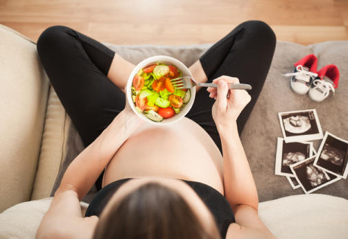 Femme enceinte tenant un bol d'aliments sains