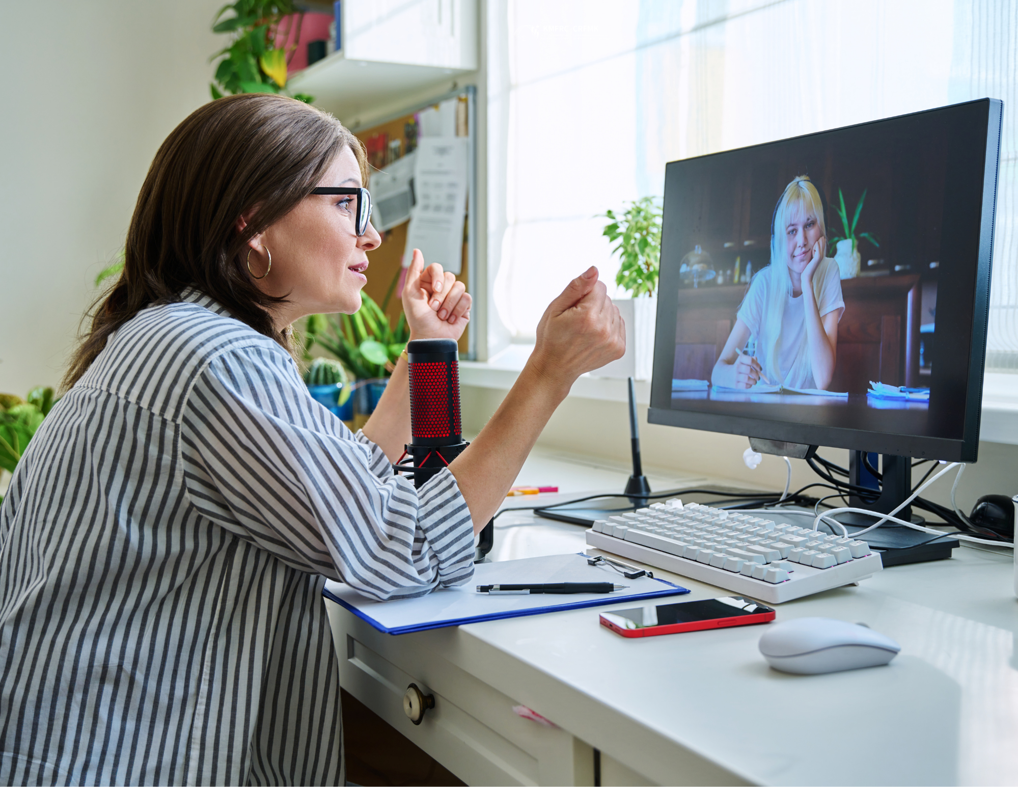 Une personne participant à un appel vidéo depuis son bureau à domicile, en train de discuter avec quelqu'un sur un écran d'ordinateur, dans un espace de travail lumineux agrémenté de plantes et de mat