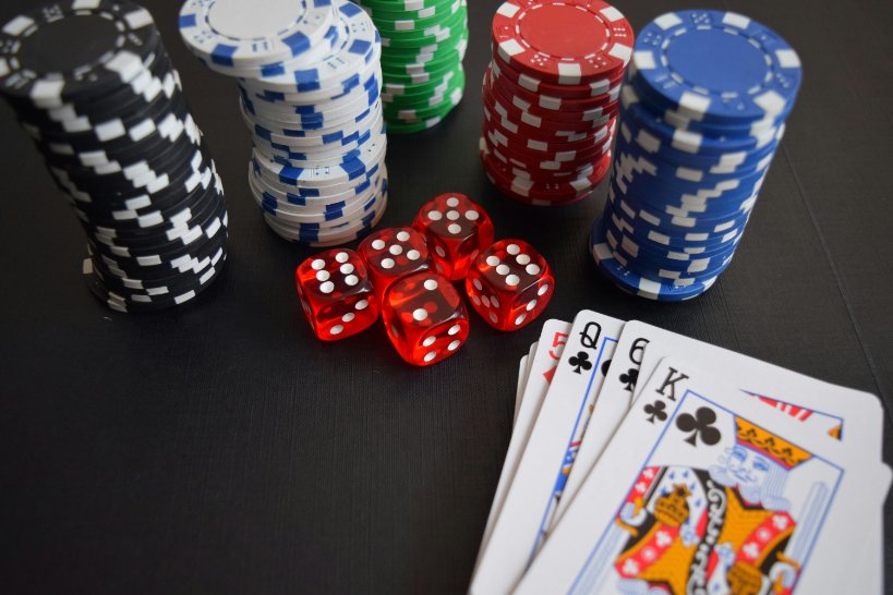 Quelques cartes à jouer, 5 dés et des piles de jetons de poker sur une table